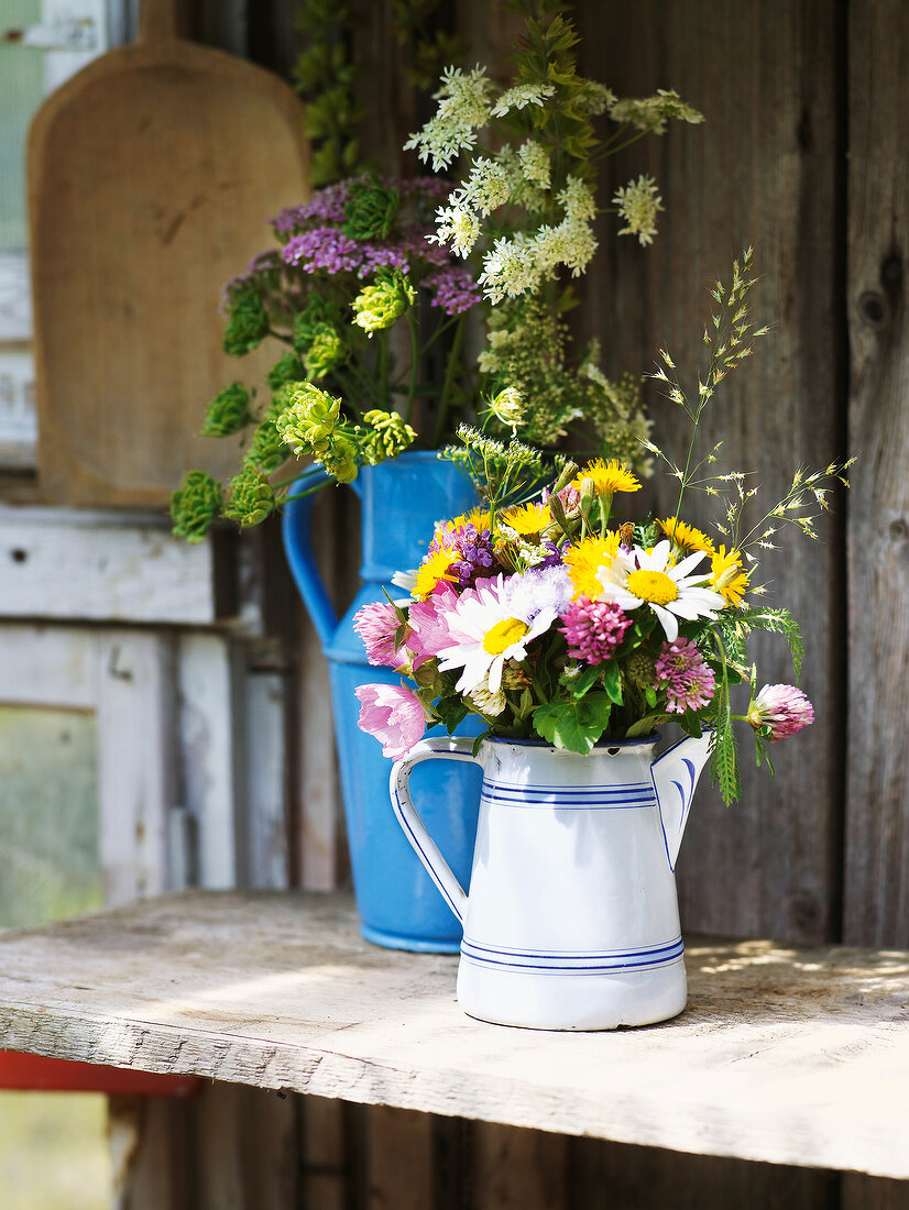 Various summer flowers and bouquet of flower in pots in summer kitchen
