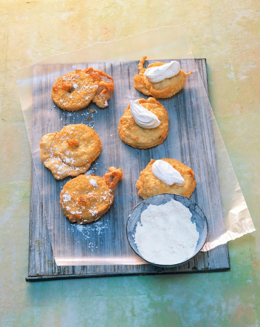 Apple fritters in peanut oil with mascarpone on baking sheet
