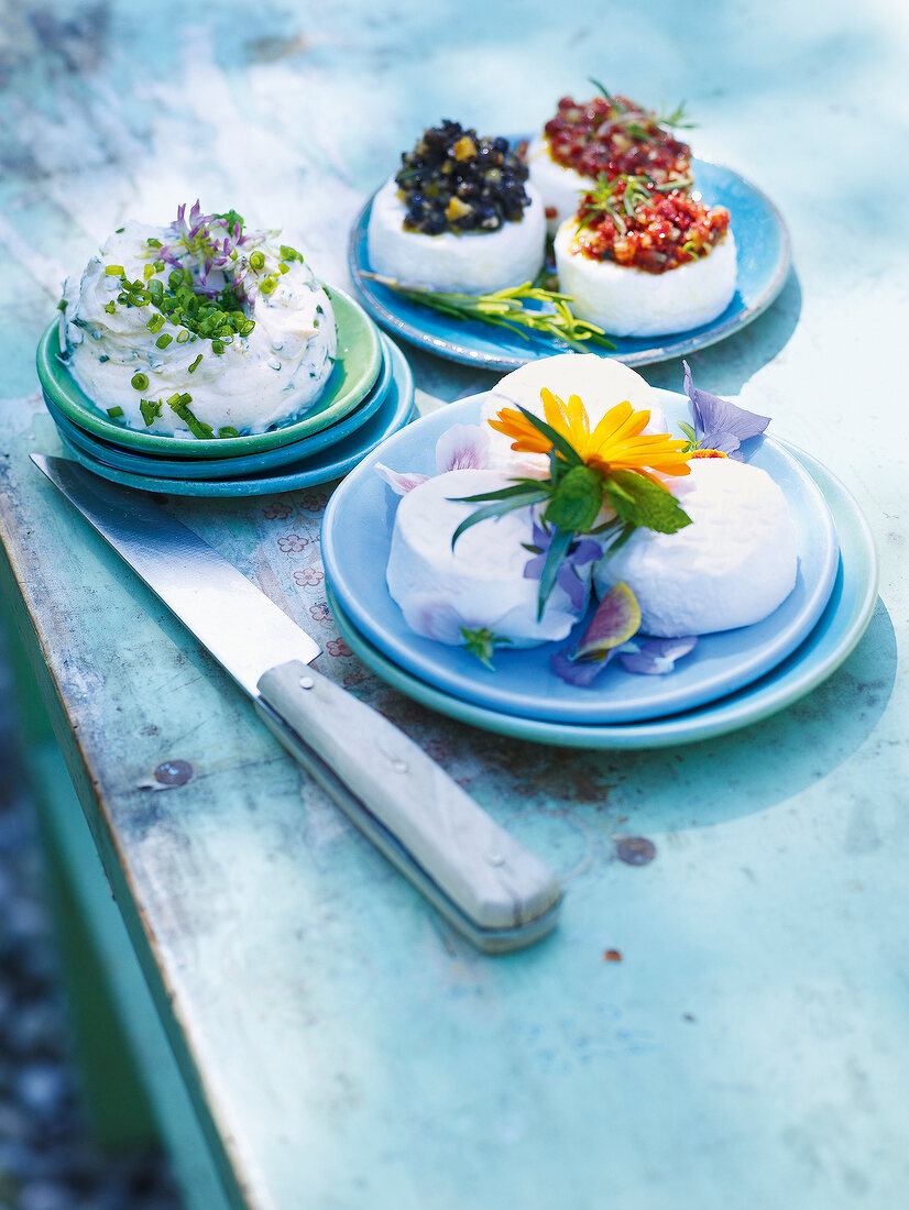 Three different dishes of goat cheese garnished with flowers and berries on plate