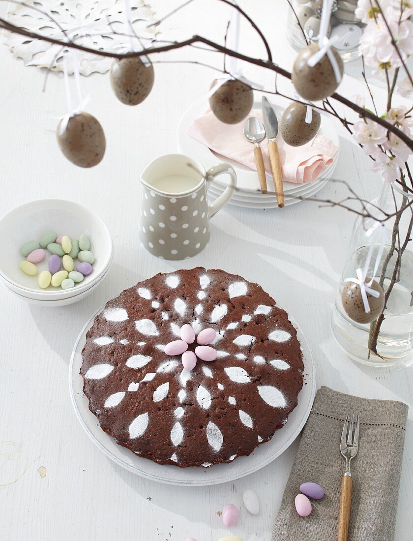 Chocolate cake decorated with icing on a table laid for Easter