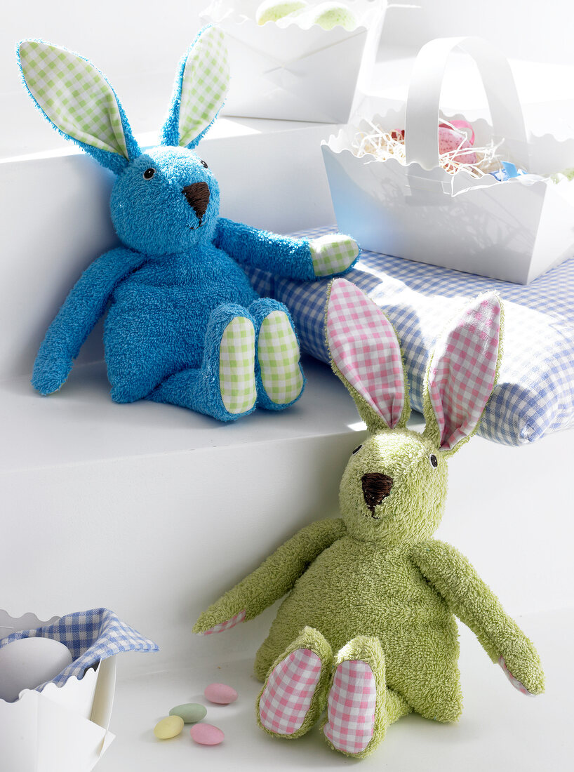 Self-made rabbit out of terry towels in blue and green on white surface