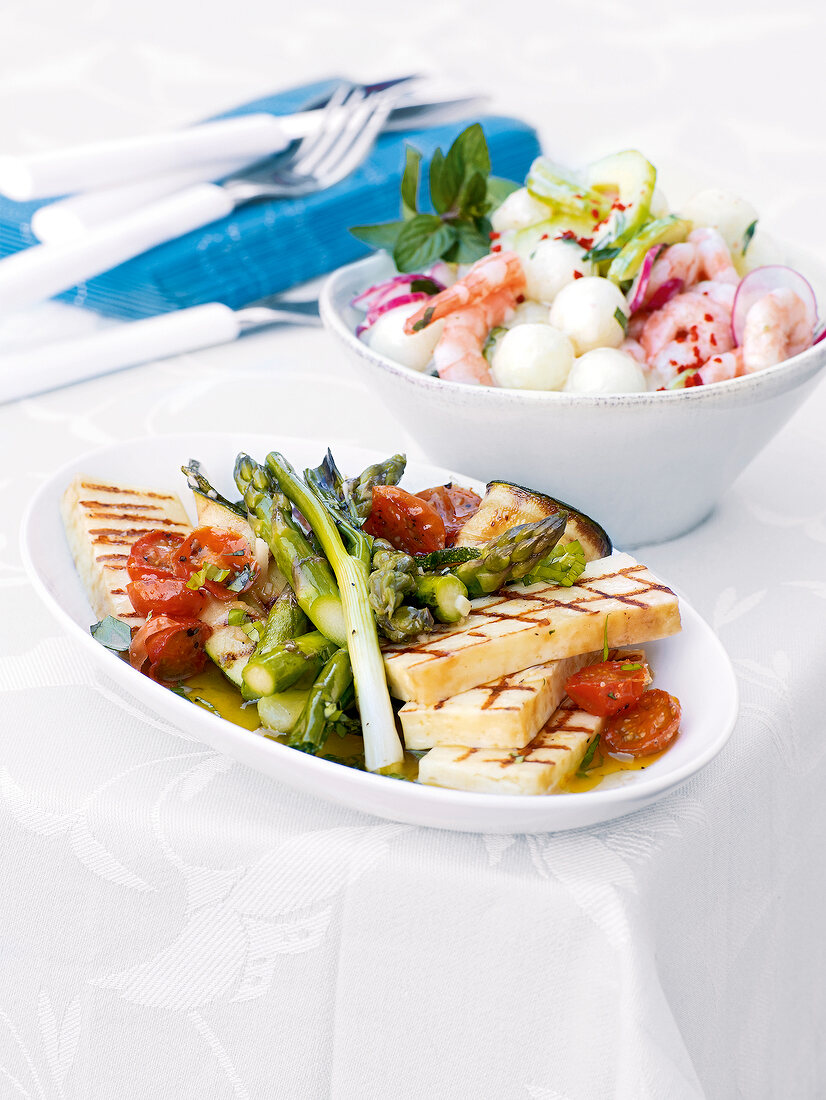 Marinated summer vegetables in serving dish and cucumber melon salad in bowl