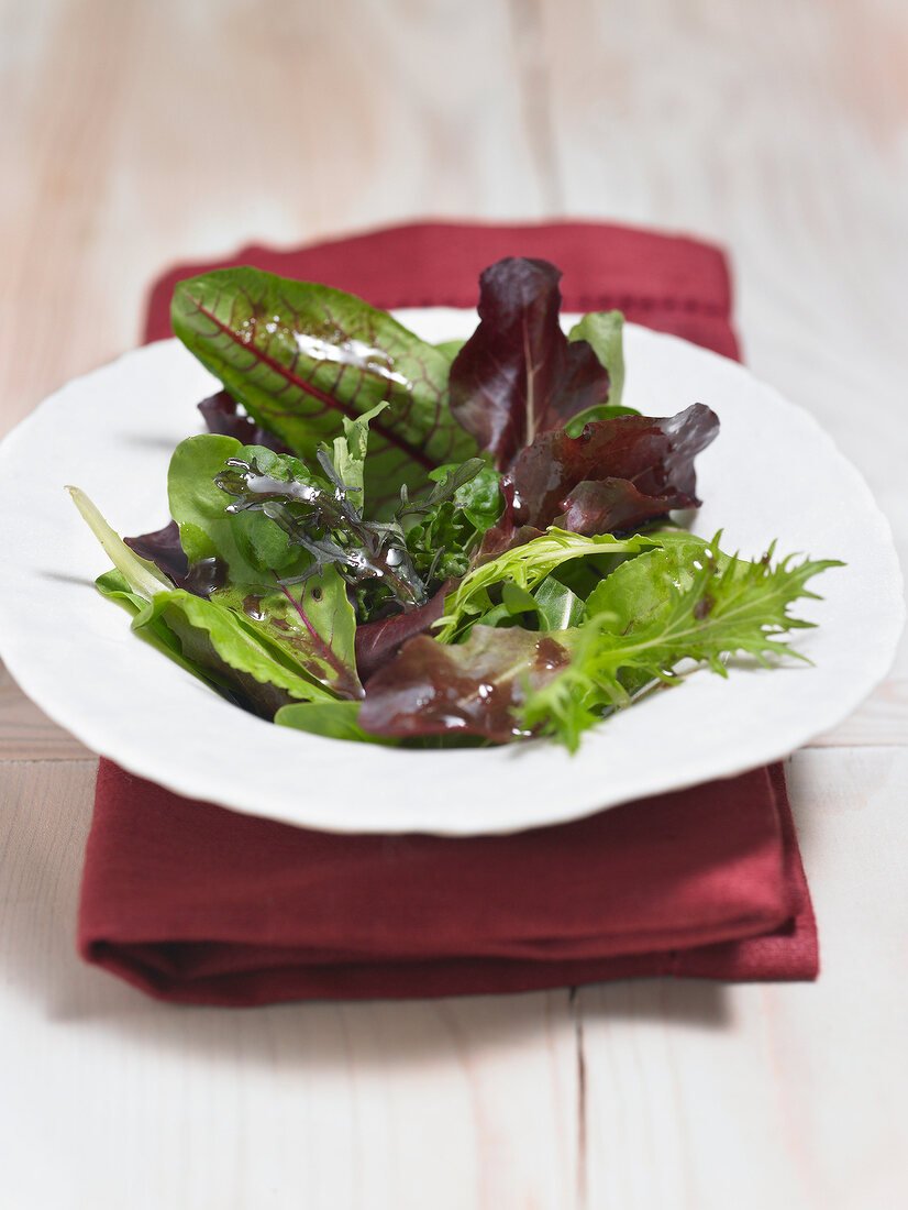 Bowl of lettuce leaves on red folded napkin