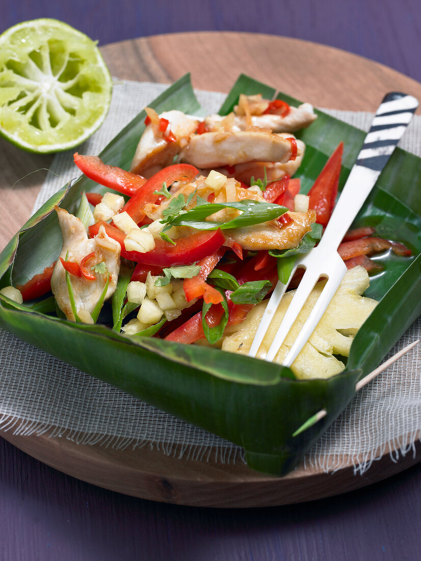 Chicken salad with pineapple and fork in leaf bowl