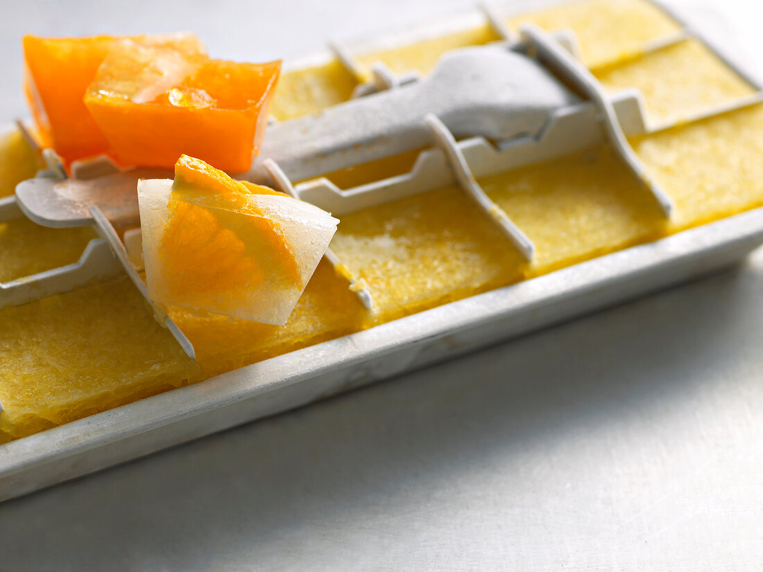 Close-up of oranges in ice cubes on ice tray