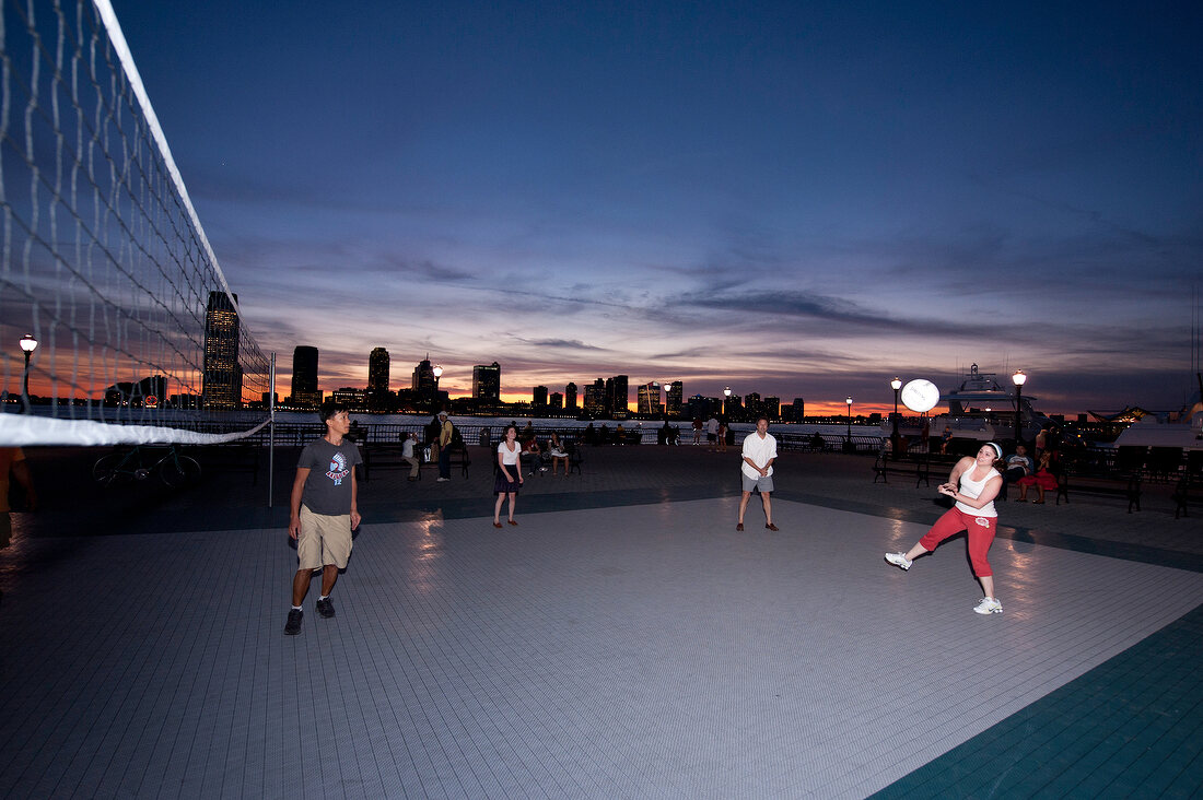People playing volleyball at the bank of Hudson River at dusk in New York, USA