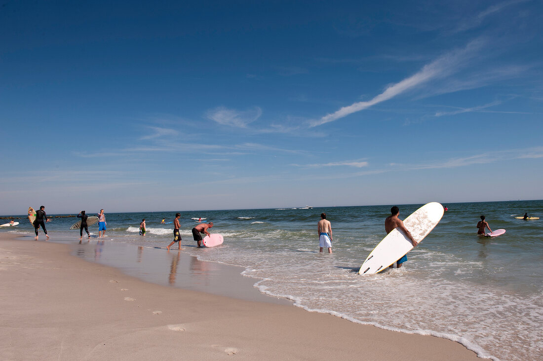 Man holding surfboard at Long Beach in New York, USA