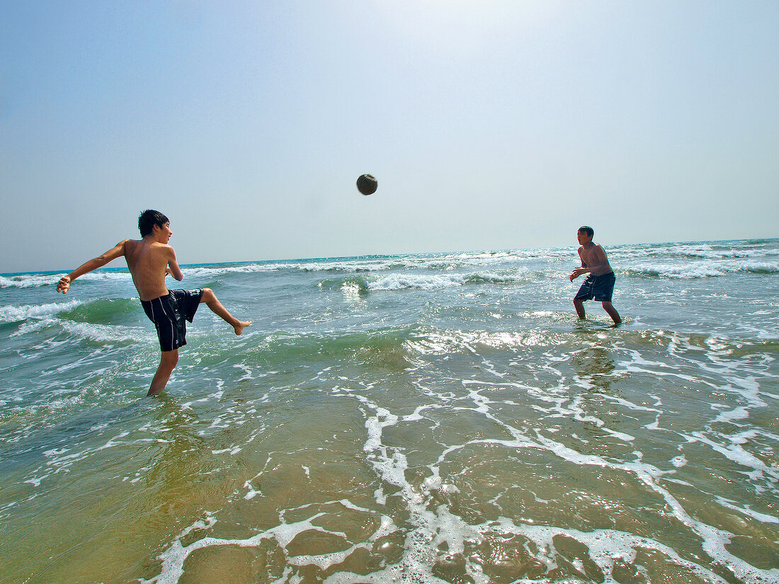 Boys playing football in water at Patara beach, Turkey