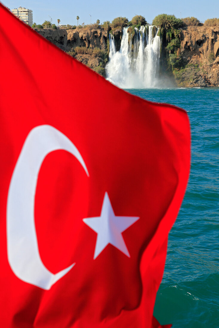 Close-up of Turkish flag in front of Duden Waterfall at Lara rocks in Antalya, Turkey