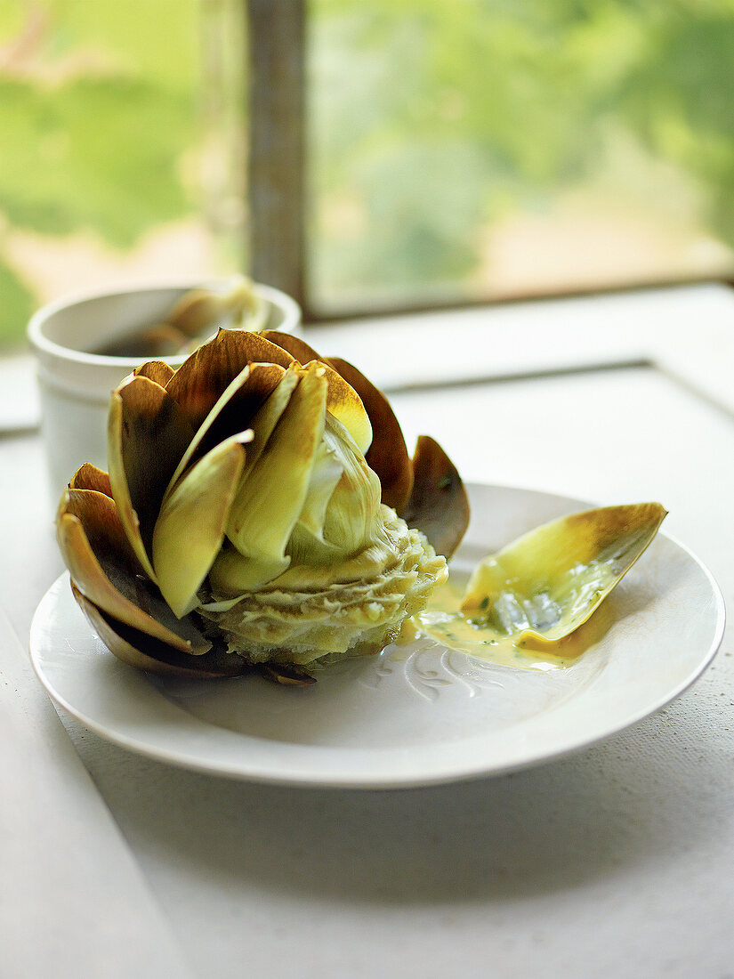 Close-up of cooked artichoke with leaves on plate
