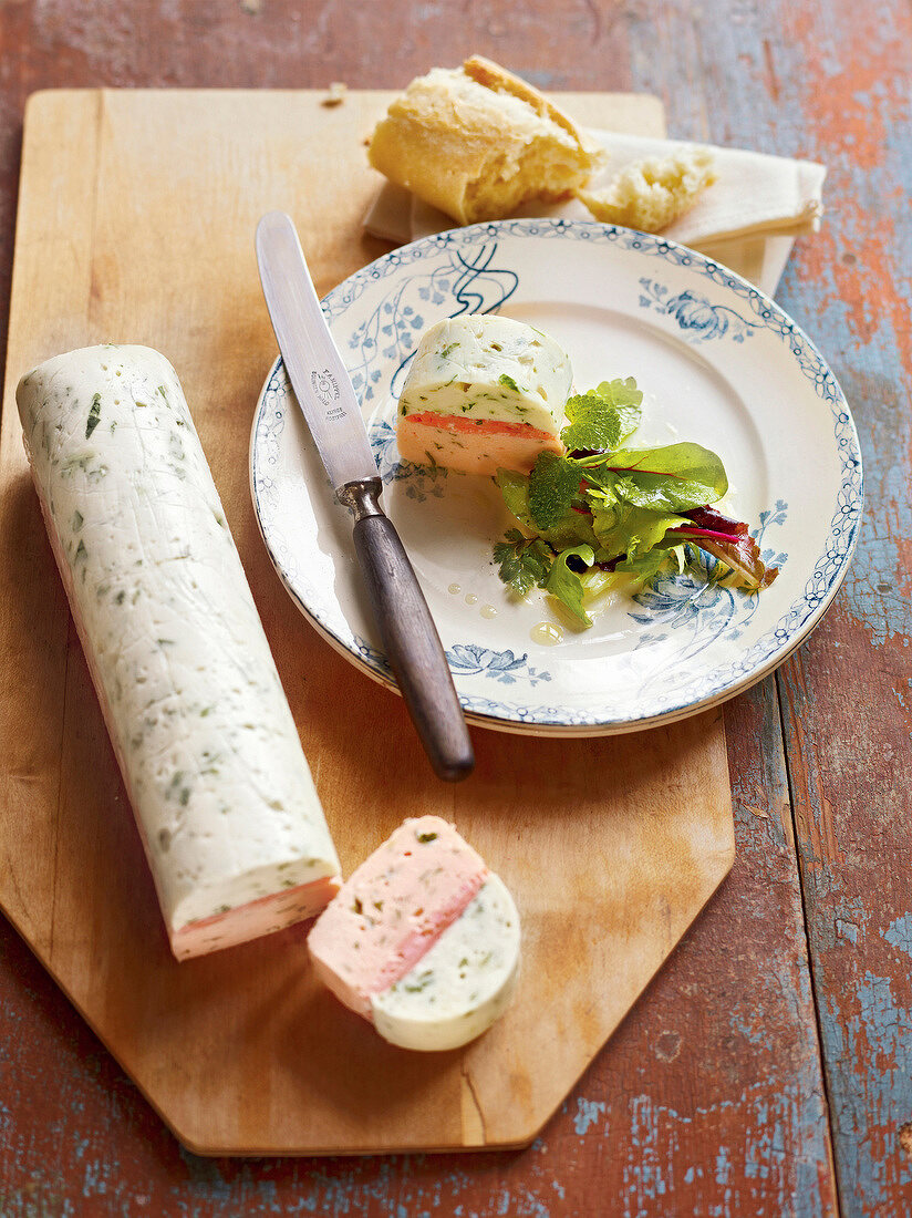 Piece of zander and salmon terrine with herb salad on plate, France