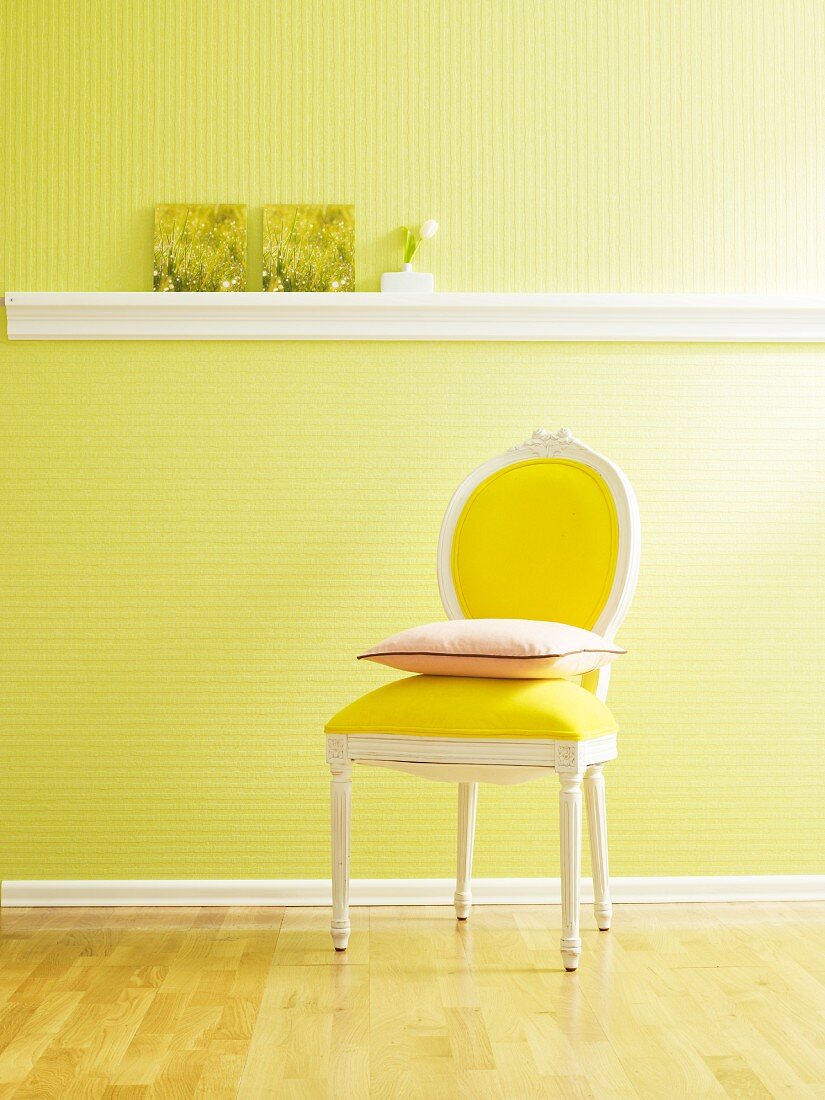 Cushion on chair against wall with green wallpaper and stucco dado rail used as shelf