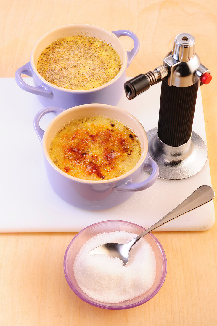 Creme brulee with desserts and sugar on cutting board