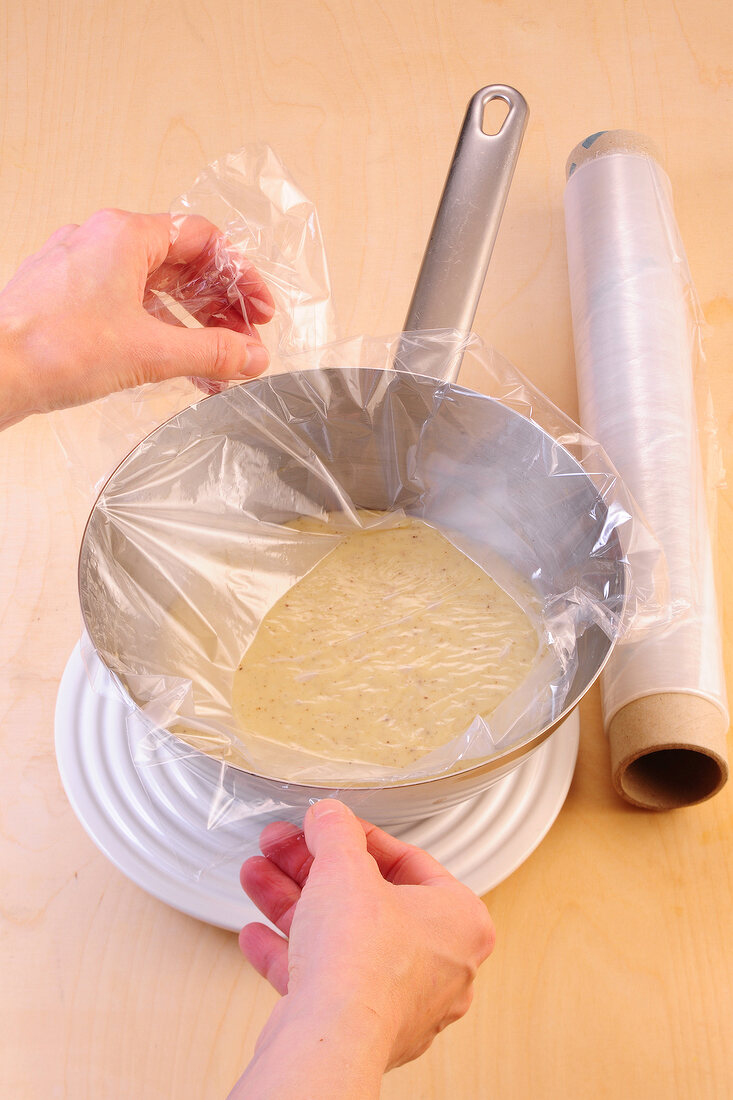 Covering cream in sauce pan with transparent foil for preparation of desserts, step 2
