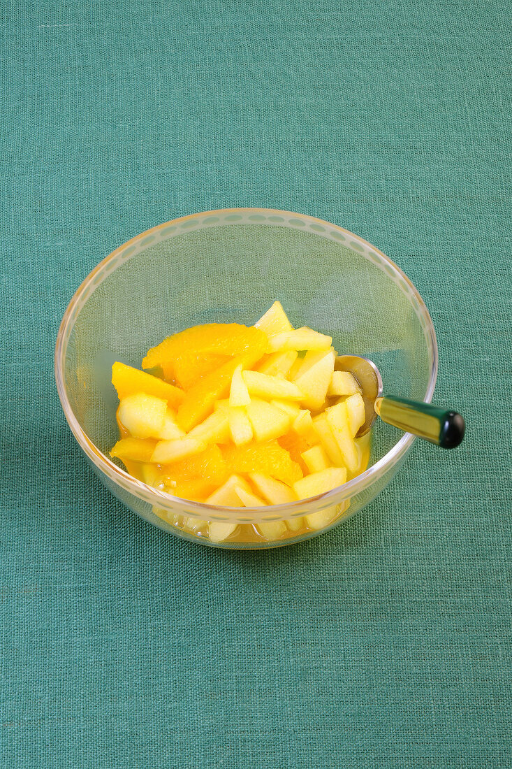 Apple and orange compote in glass bowl with spoon