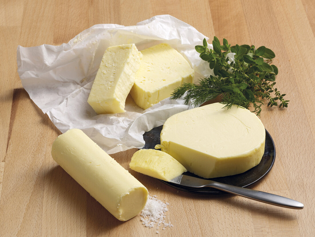 Various types of butter with fresh herbs on wooden board