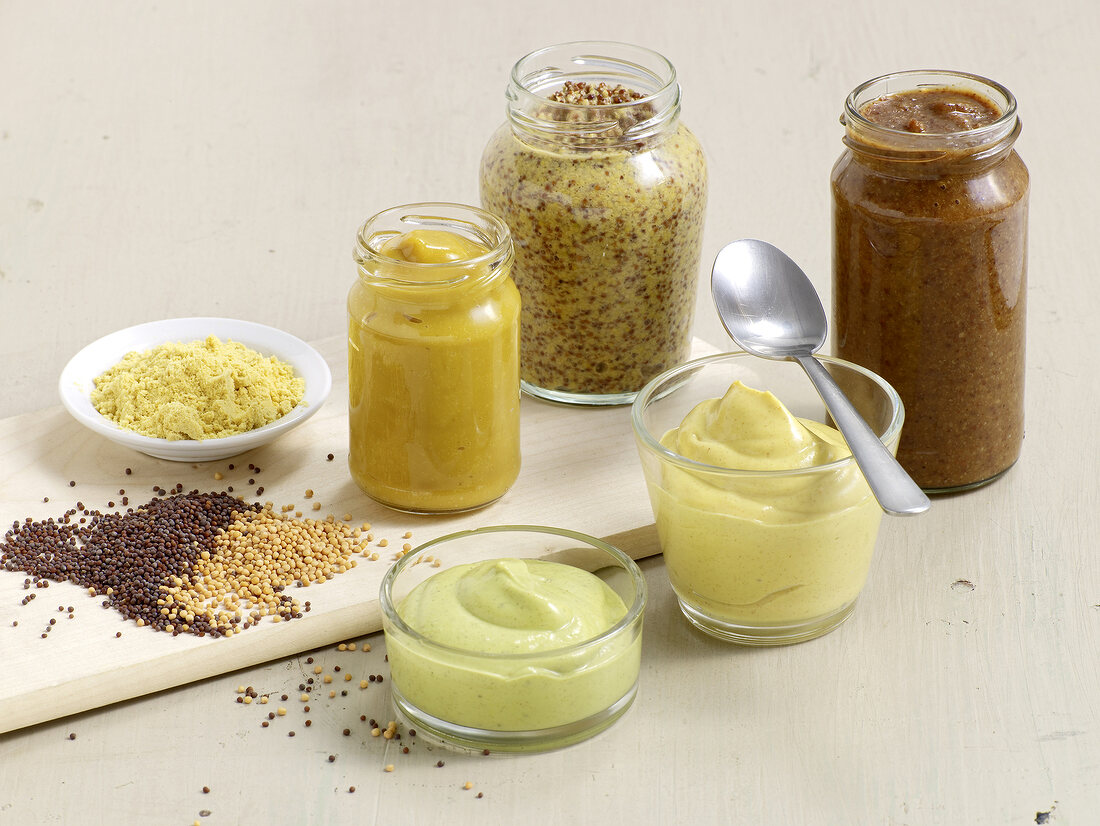 Different types of mustard paste in jars with mustard seeds