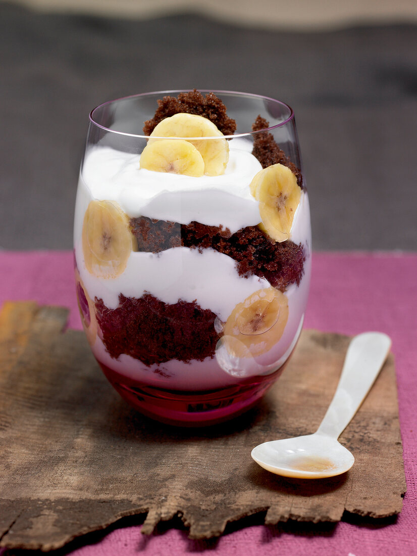 Close-up of banana trifle in glass with spoon