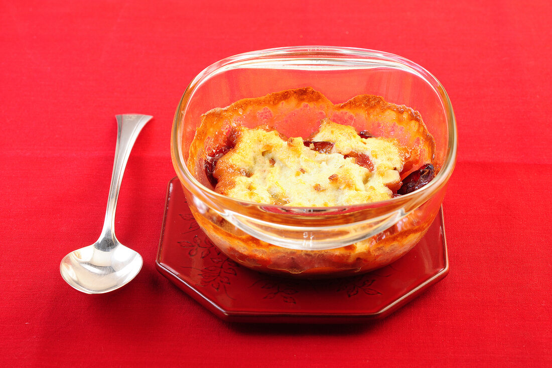 Plum cobbler in serving dish on red background
