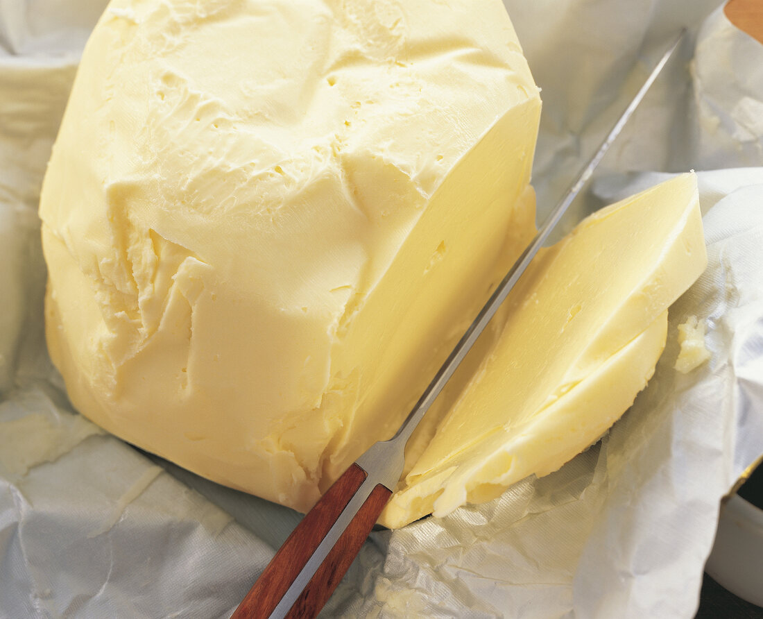 Close-up of butter being sliced on butter paper