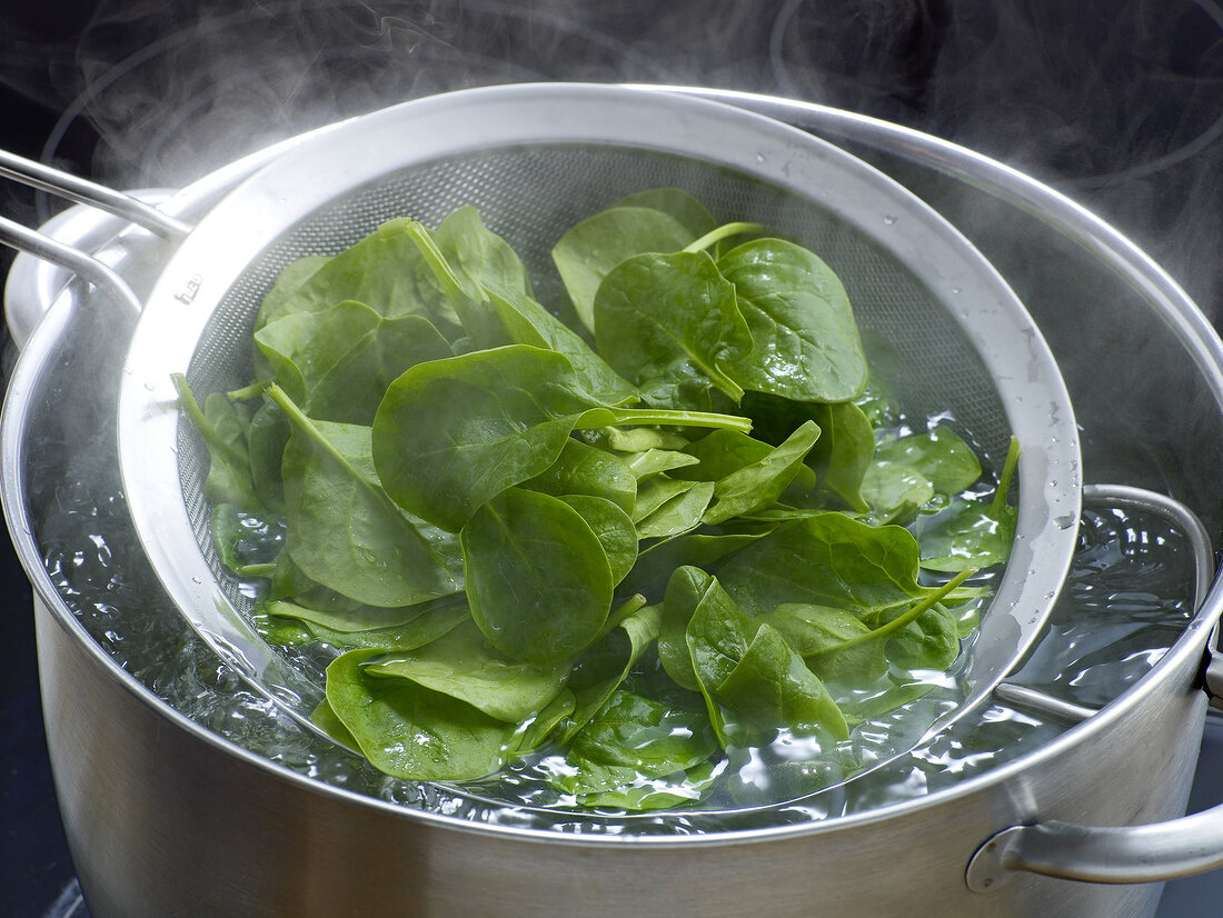 Close-up of blanched spinach on sieve for preparation of sauce, step 1
