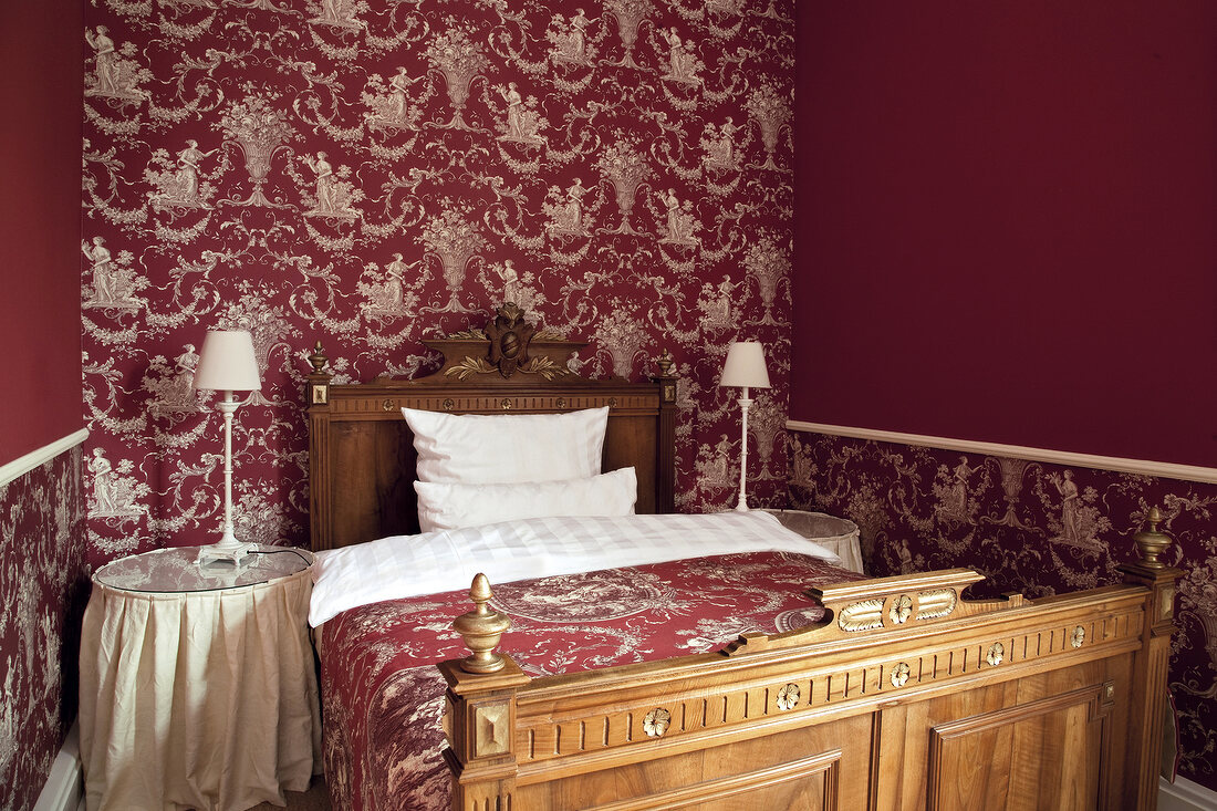 Bedroom with bed, side table, side lamps and pink coloured walls