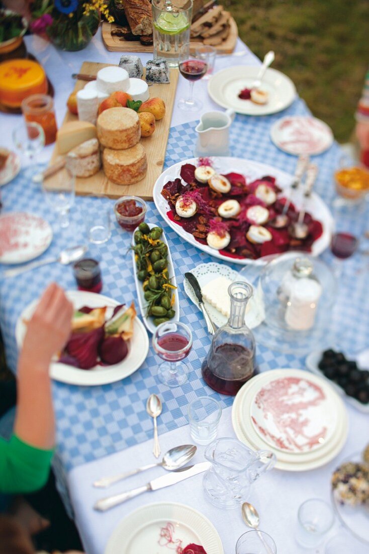 A table laid outside with canapés, cheese and wine