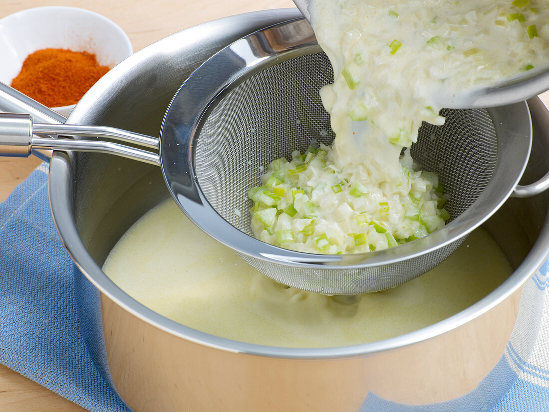 Broth being removed from vegetables by using sieve for preparation of sauce, step 1