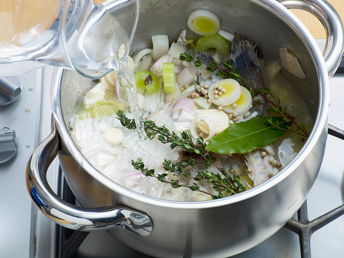 Adding water and spices in pan for preparation of fish stock, step 4