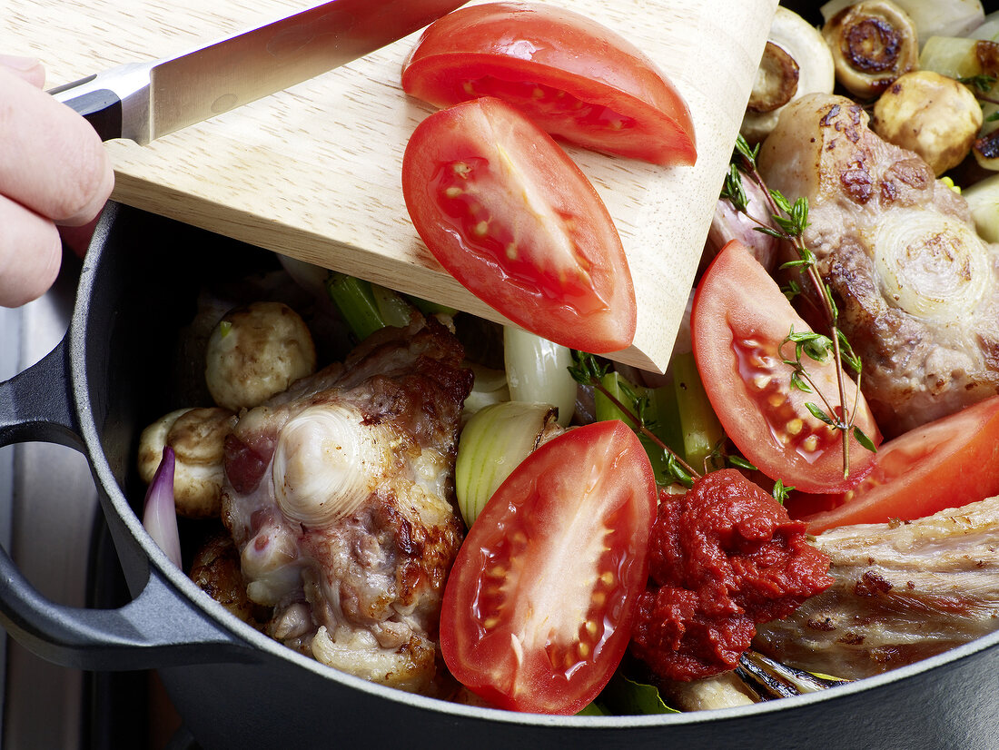 Close-up of tomatoes being added in pan for preparation of veal jus, step 5