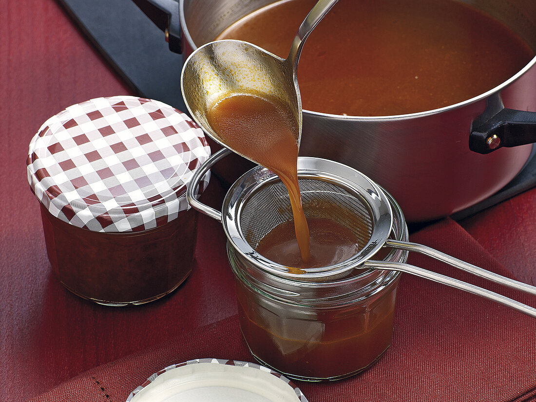 Filling veal jus in glass jars with ladle, step 10
