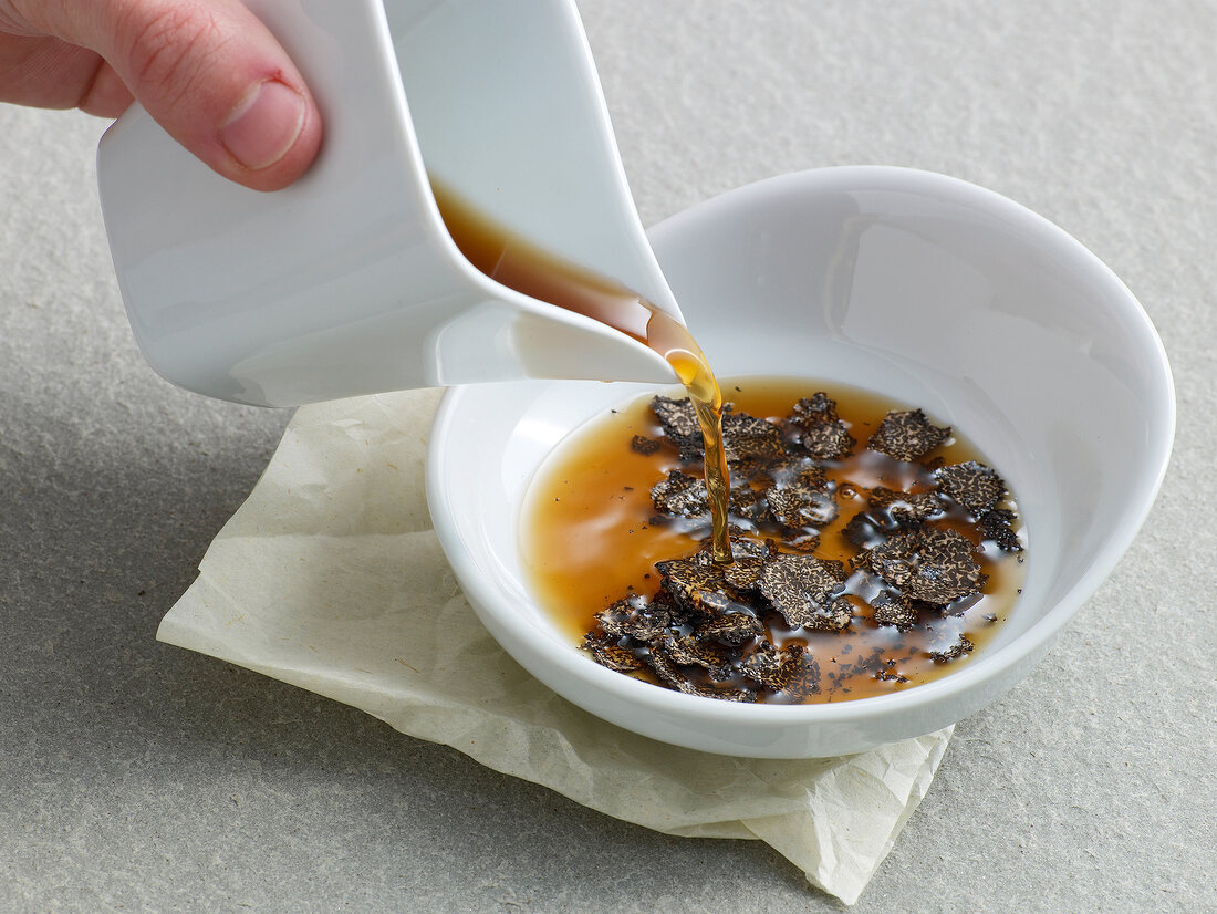 Pouring liquid in bowl with truffle slices for preparation of truffle essence, step 2