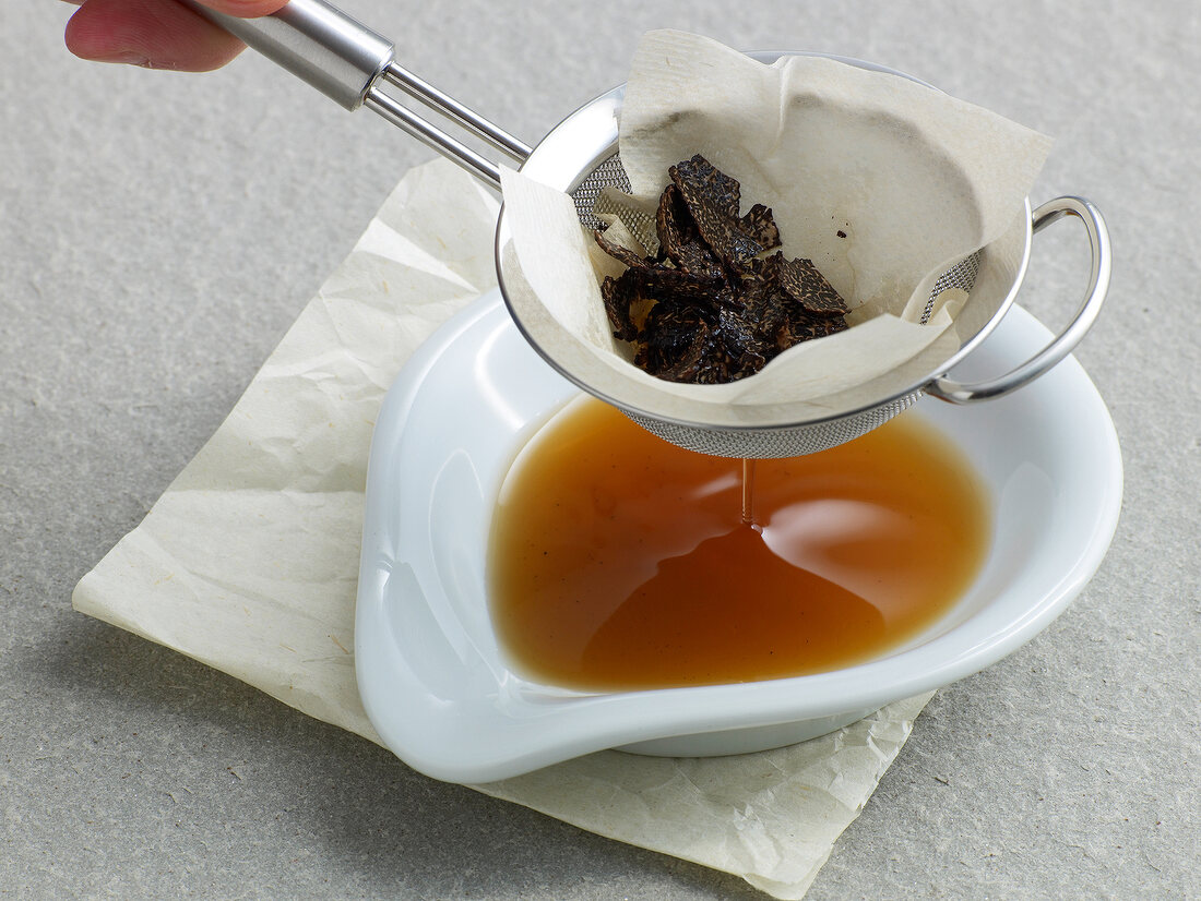 Filtering truffle liquid in bowl with sieve for preparation of truffle essence, step 5