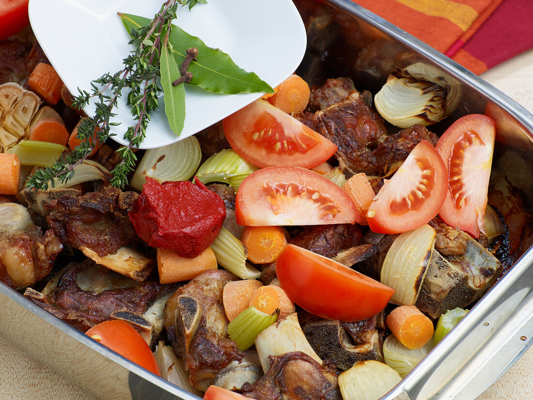 Adding spices in baking tray with roasted veal for preparation of veal stock, step 5