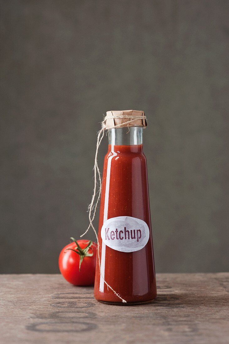 Eine Flasche selbst gemachter Ketchup und eine Tomate