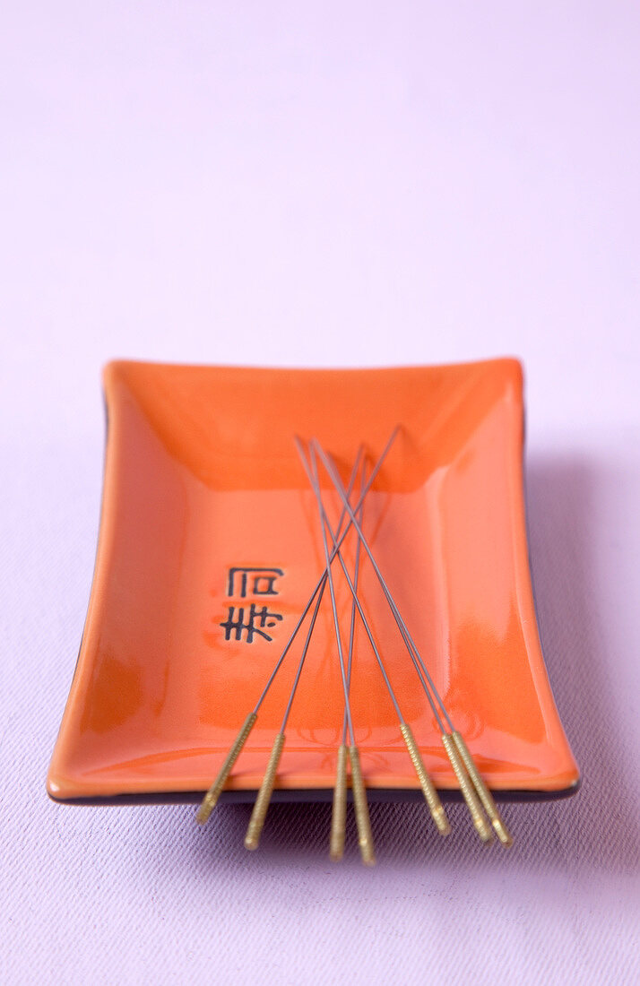 Acupuncture needles in an orange and black tray