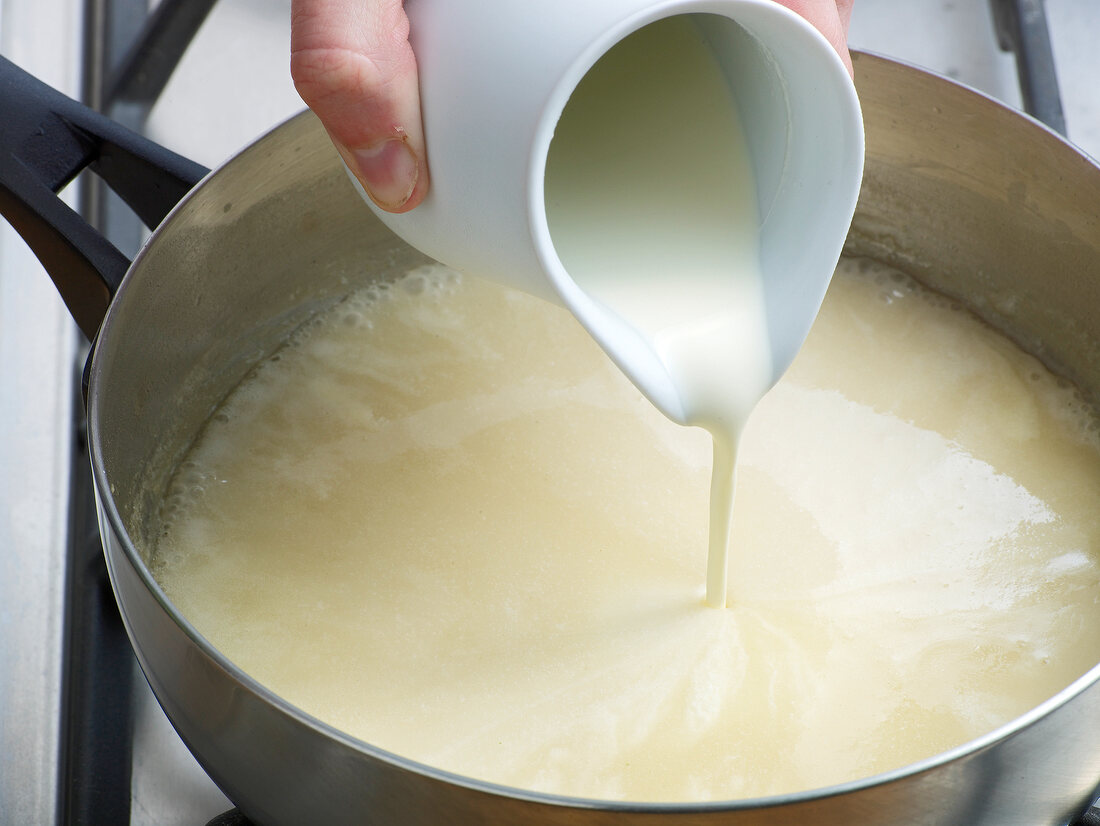 Close-up of cream being poured in mixture for preparation of poultry veloute, step 4