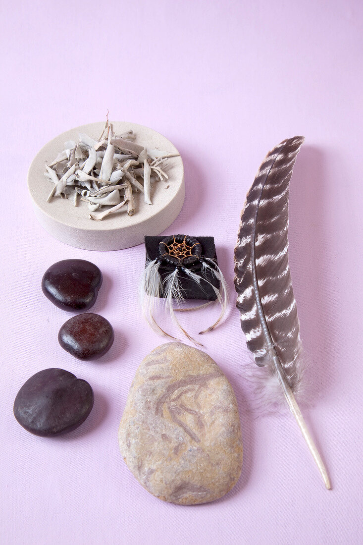 Stones, feather and other alternative medicine on purple background