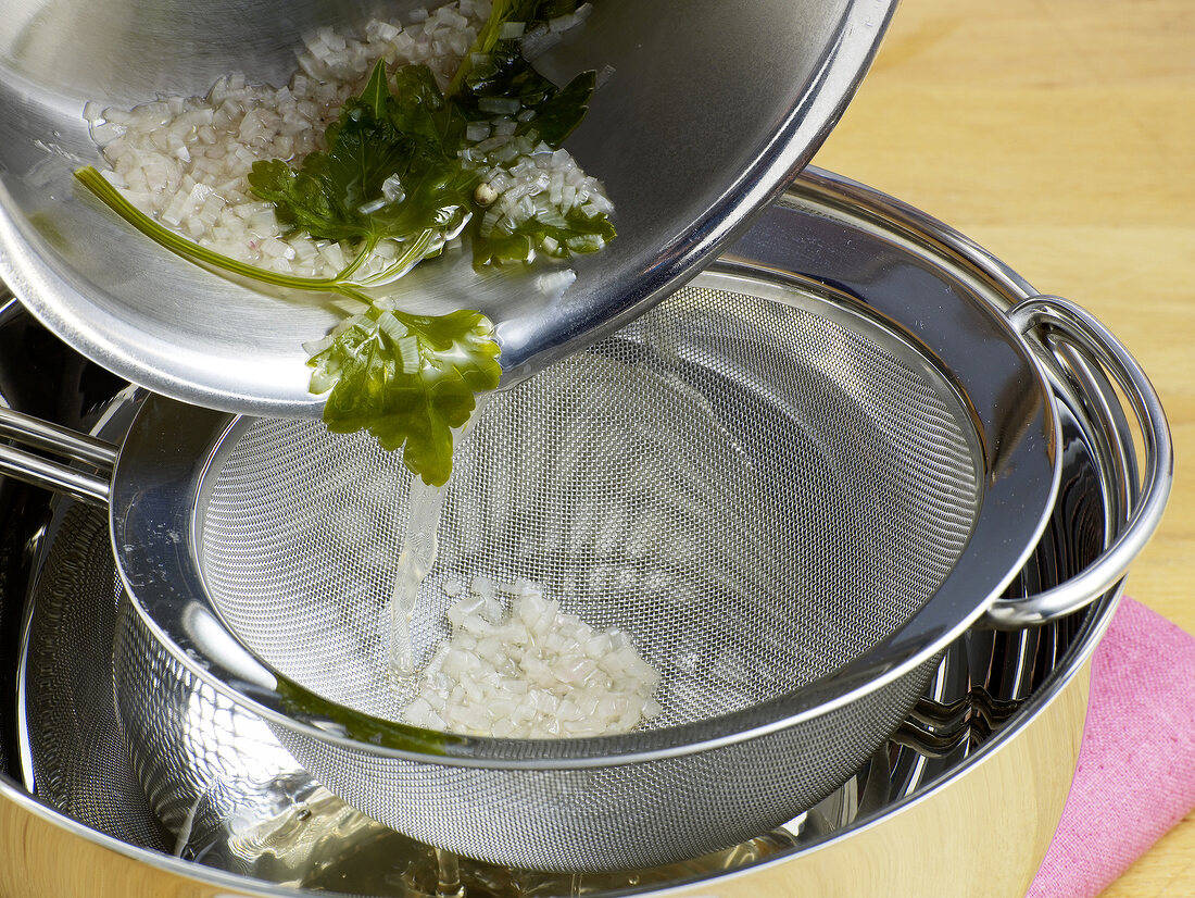 Mixture being strained through sieve for preparation of hollandaise sauce, step 2
