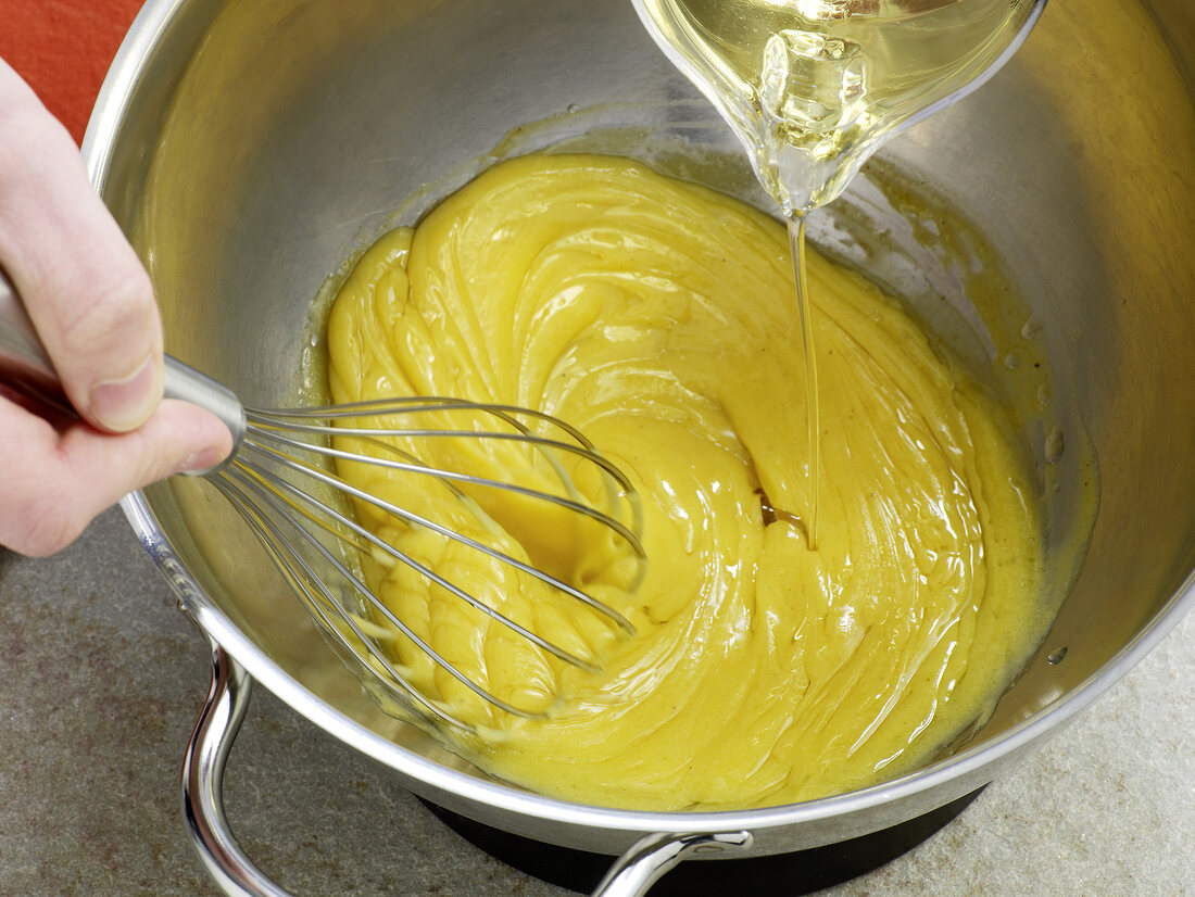 Close-up of oil being poured in mayonnaise and egg yolks mixture, step 4