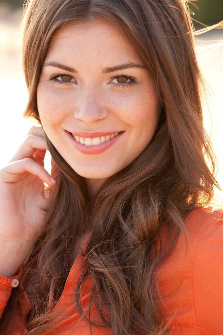 Portrait of beautiful woman with brown hair wearing orange top