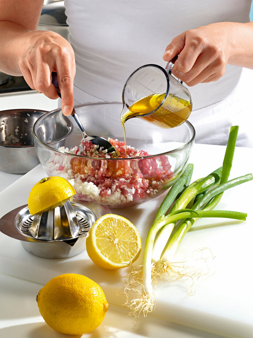 Close-up of hand pouring oil in chopped tuna for preparation of tuna tartare