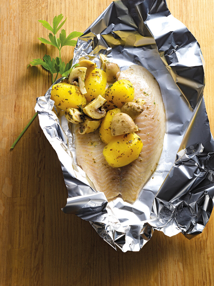 Tilapia with potatoes and mushrooms in silver foil 