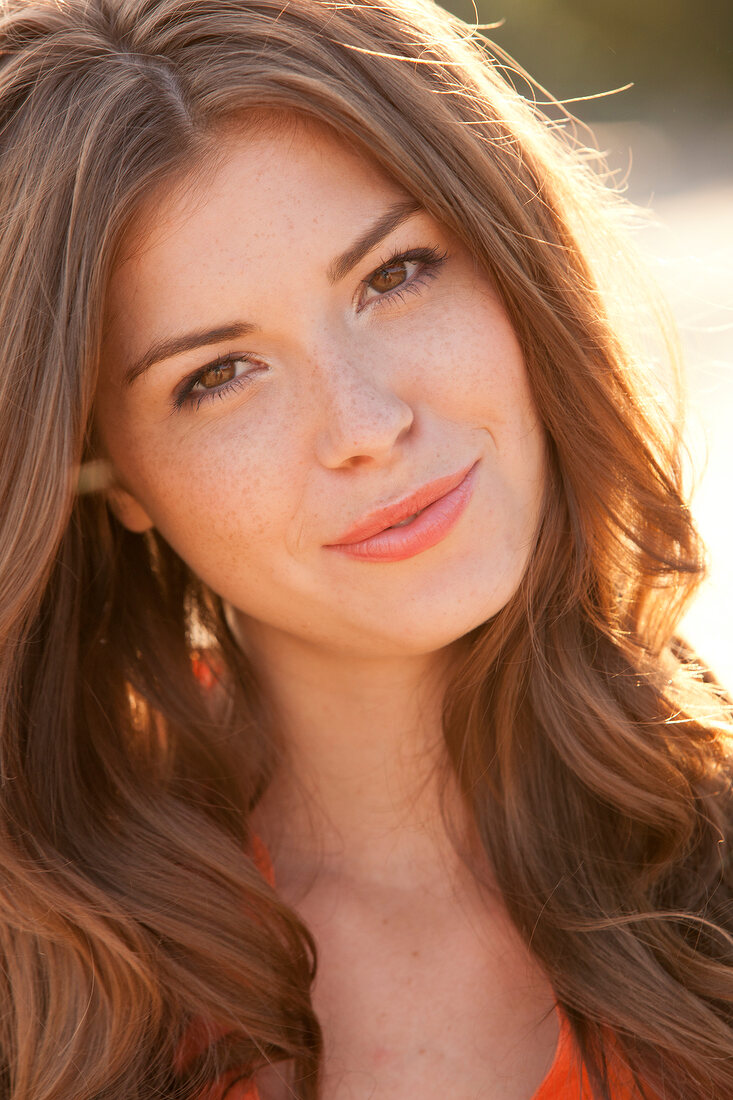 Portrait of beautiful woman with brown hair wearing orange top