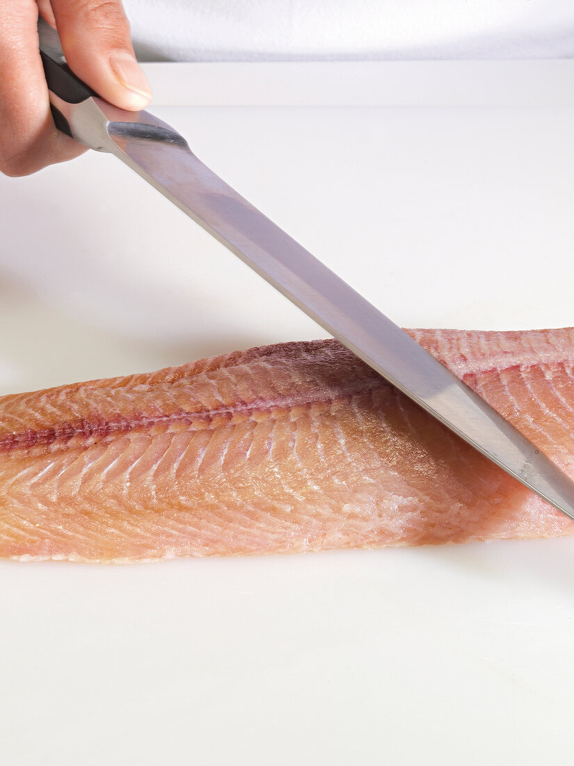 Close-up of hand cutting fish fillet with knife