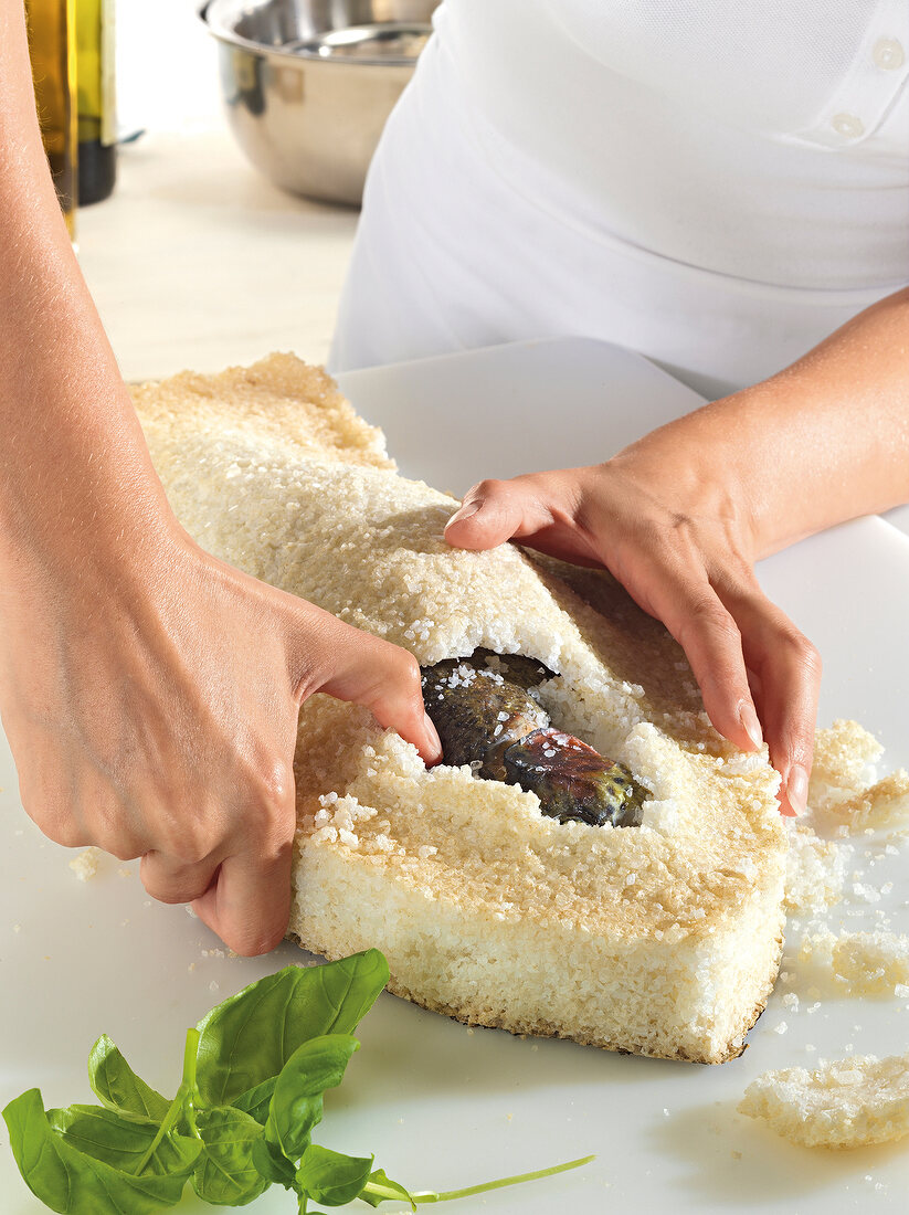 Close-up of woman removing fish from salt crust