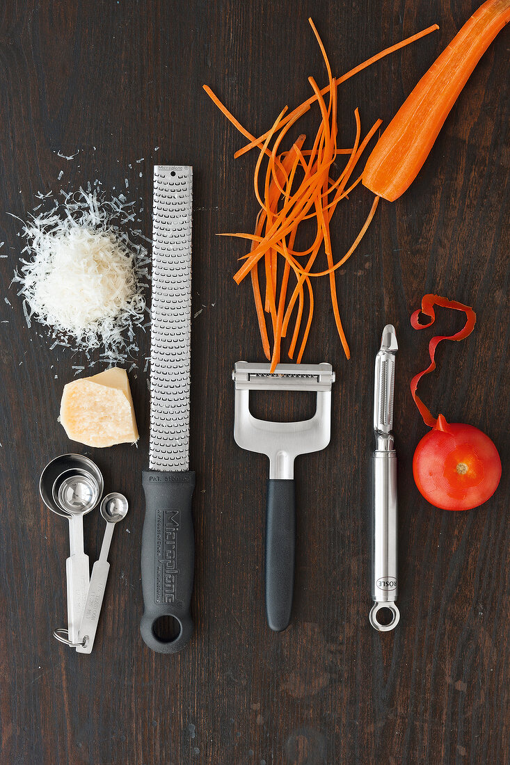 Set of kitchen utensils, vegetables, grater, shredded cheese and carrot on wooden board
