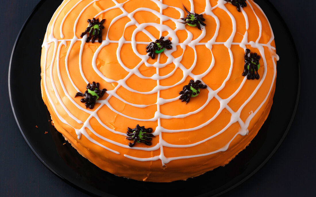 Cake decorated with spider web design on black plate