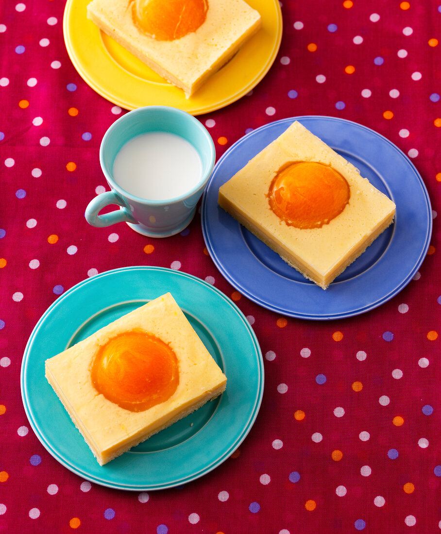 Three pieces of fried cake and cup of milk on tablecloth