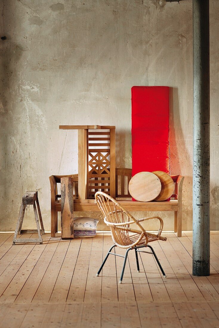 A rattan chair opposite wooden garden benches in a loft-style room